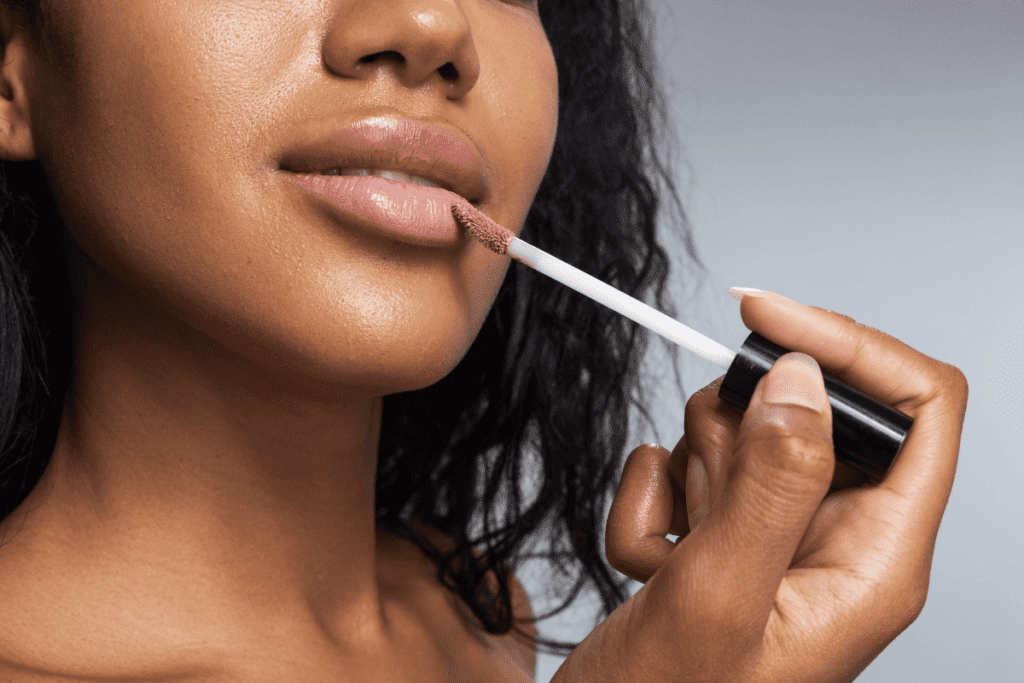 Mulher negra aplicando o Lip Gloss