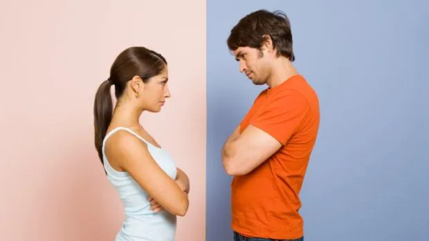 Homem de camiseta laranja e mulher de camiseta branca se encaram, ao fundo do homem há uma parede azul, ao fundo da mulher uma parede rosa